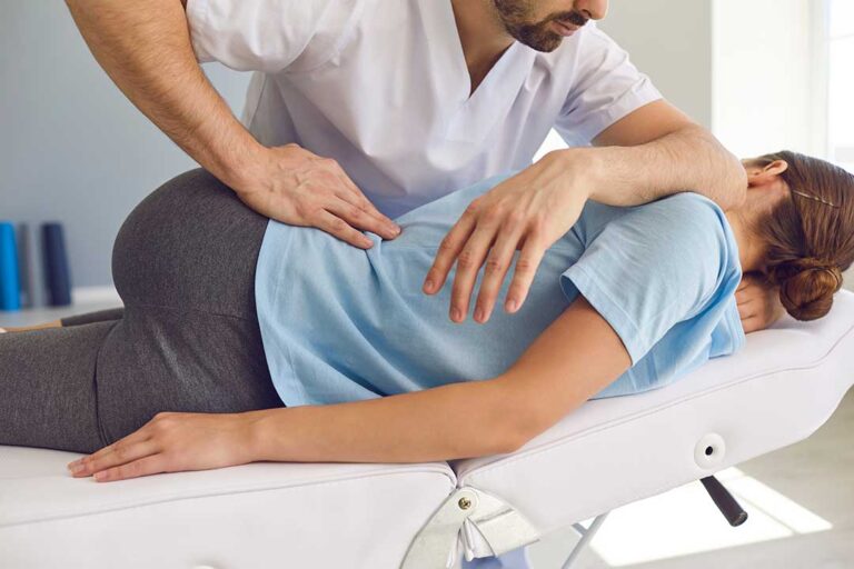 A close-up of a practitioner using a stainless steel tool on a patient's forearm during therapy.