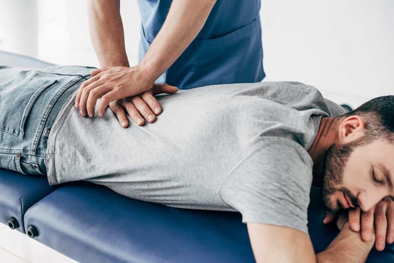 A person lying on a chiropractic adjustment table while a practitioner gently checks spinal alignment.